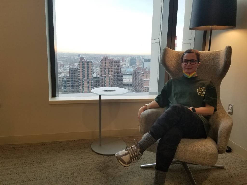 Picture of me sitting in a swanky waiting room chair with Roosevelt island out the window.
