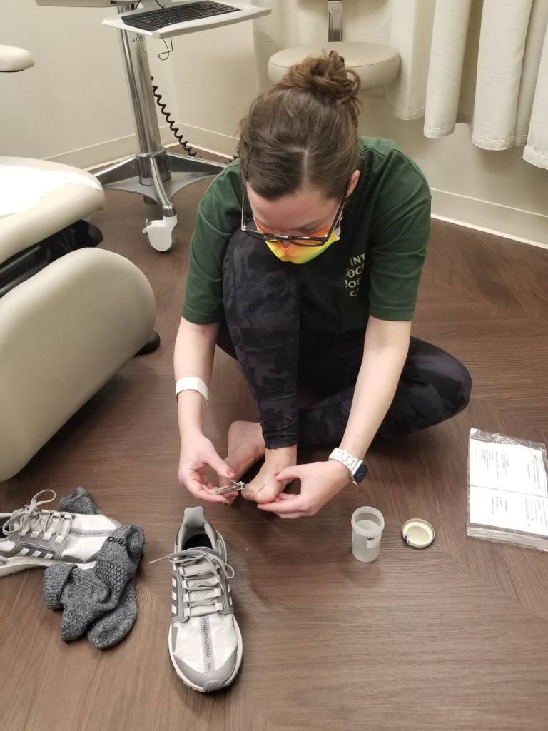 Picture of me on the floor of a medical examination room, clipping my toenails into a lab jar.